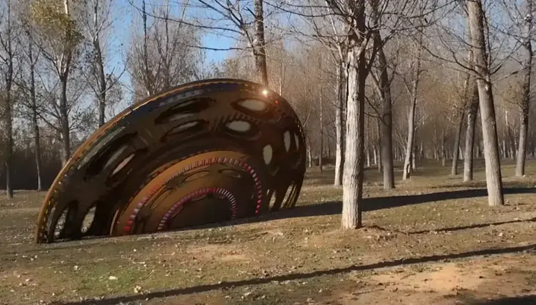 A saucer-shaped craft resting in a park, as if crash-landed