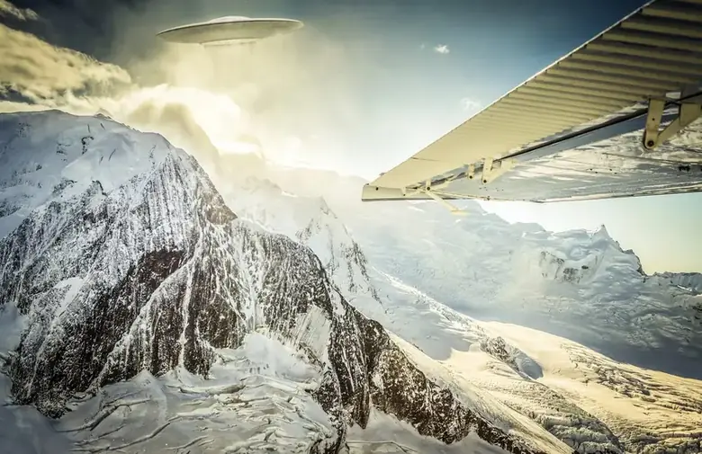 A UFO spotted from a small plane above snow-capped mountains